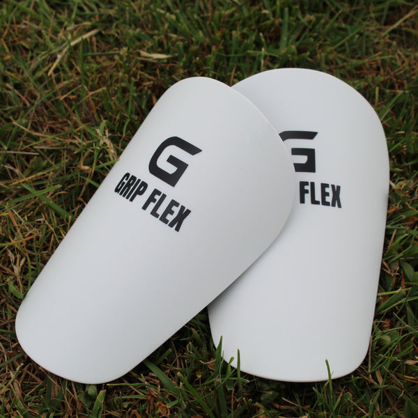 White GripFlex football shin pads with black logo branding, for athletic protection and performance.